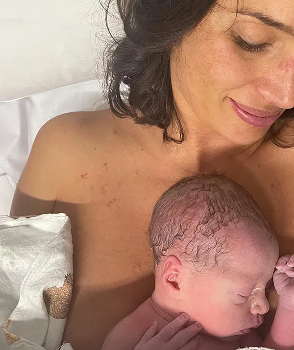 Mother smiling while holding her newborn baby on her chest.