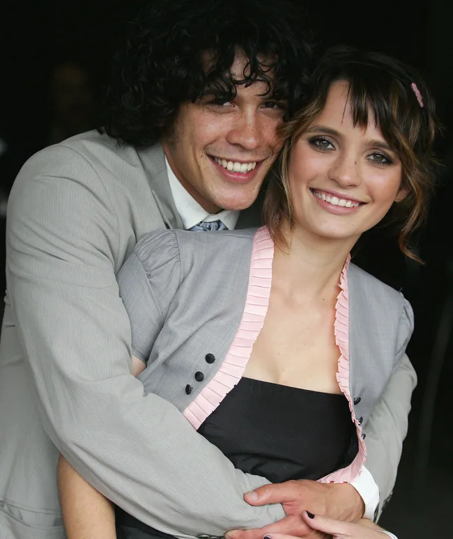 Couple smiling and embracing; man in a suit, woman in a dress with a ruffled trim.