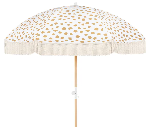 Fringed beach umbrella with gold polka dots on a white canopy.