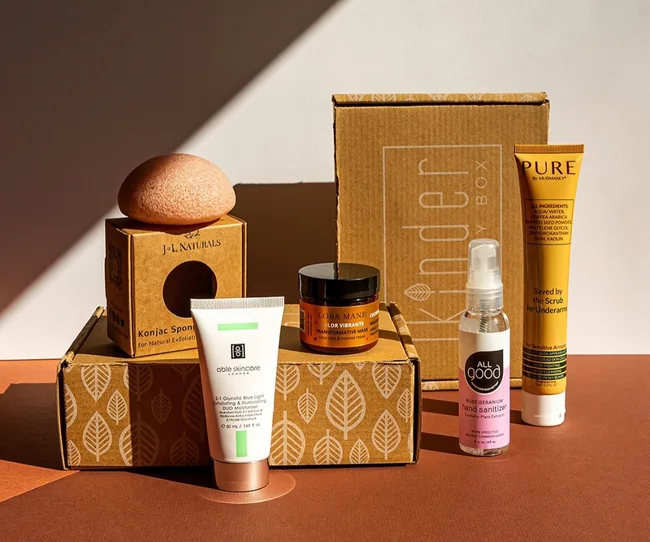 Eco-friendly beauty products arranged in sunlight, including a sponge, skincare tubes, and a Kinder Beauty Box.
