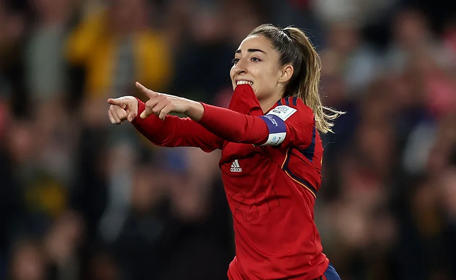 Spanish footballer celebrating a goal on the field, wearing a red jersey.