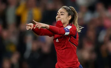 Spanish footballer celebrating a goal on the field, wearing a red jersey.