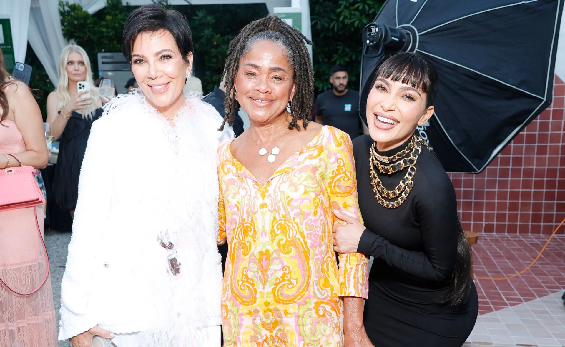 Group of three women smiling together at an outdoor event.