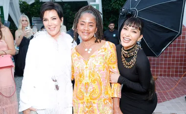 Group of three women smiling together at an outdoor event.