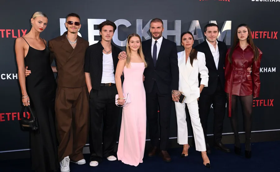 A family dressed elegantly poses together on a red carpet at a Netflix event.