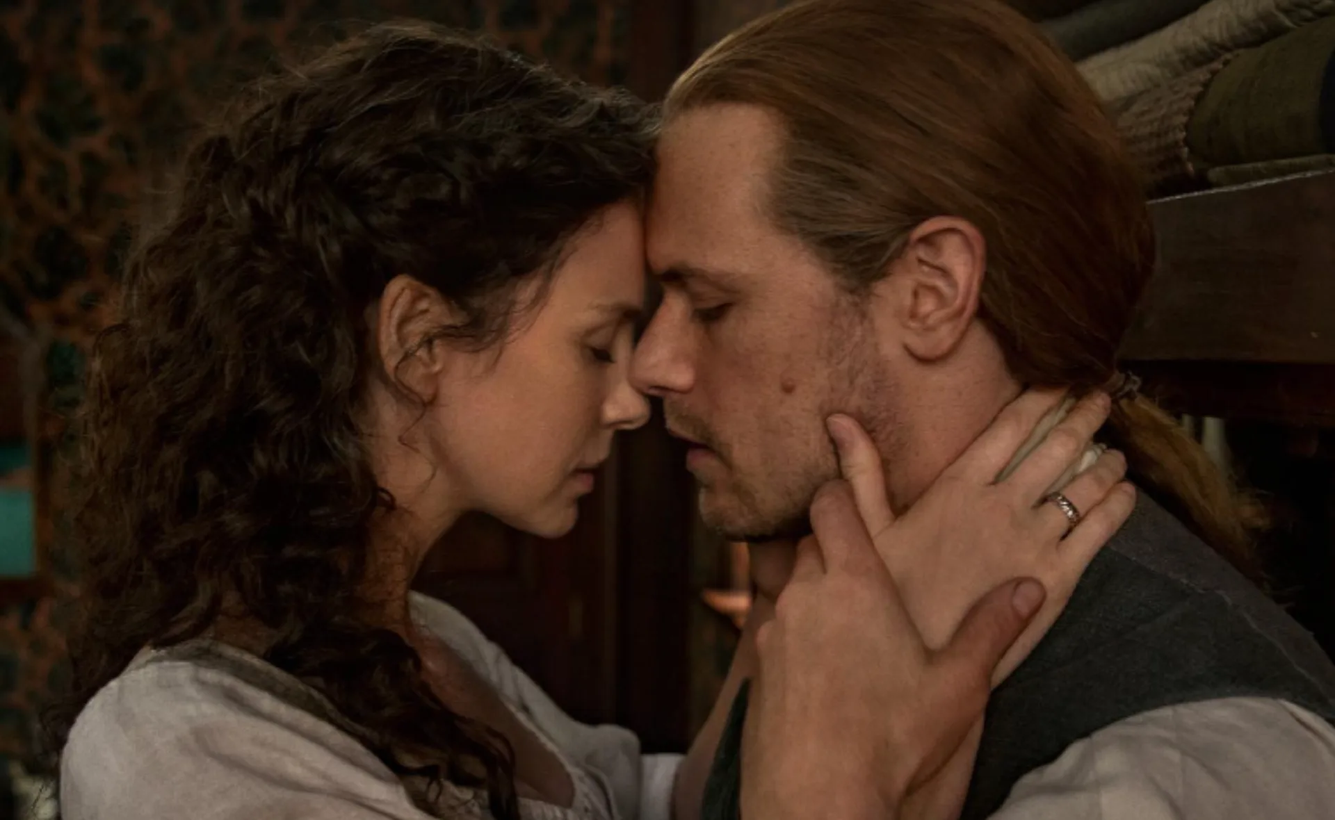 A couple with foreheads touching, eyes closed, sharing an intimate moment.
