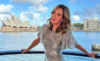 Woman in silver dress smiling with Sydney Opera House in background.