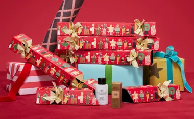 Festive red crackers with gold bows, Glasshouse fragrance, and gift boxes on a red backdrop.