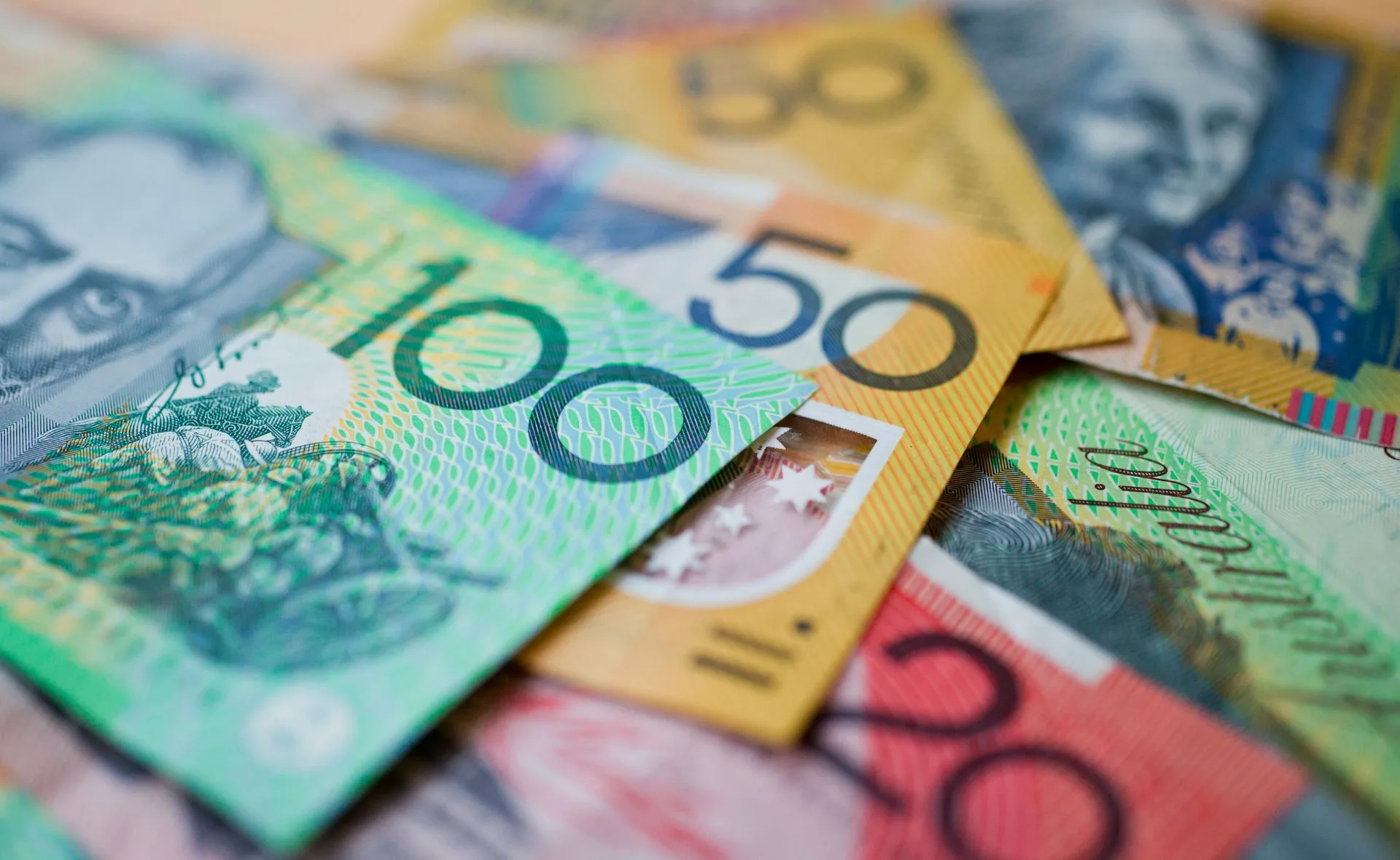 Australian dollar banknotes in various denominations scattered in a close-up view.