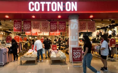 Cotton On store with Black Friday sale signs, offering 50% off. Shoppers browse clothes inside.