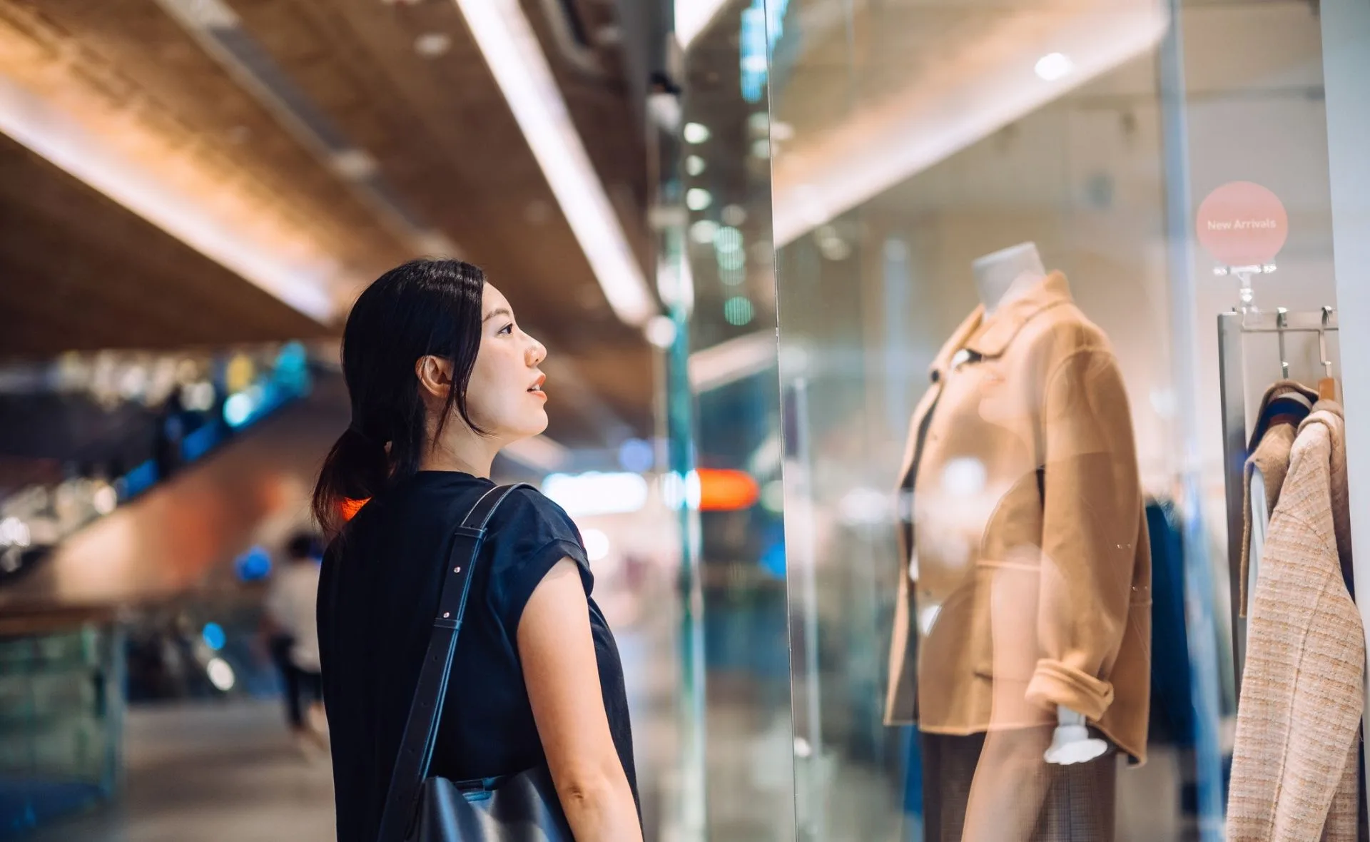 Woman looking at a mannequin's outfit, shopping for Black Friday discounts.