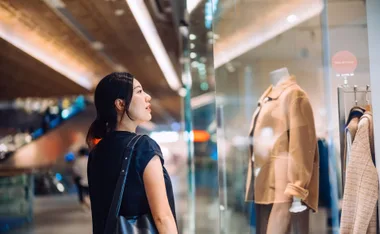 Woman looking at a mannequin's outfit, shopping for Black Friday discounts.