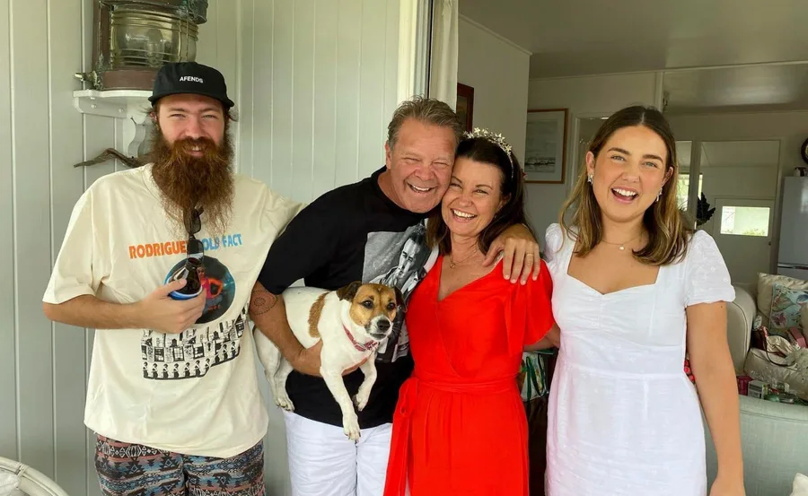 A family smiling together indoors, with someone holding a small dog.