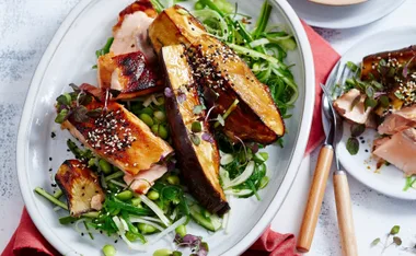 Miso-glazed salmon with daikon-cucumber salad, garnished with sesame seeds on a white plate.