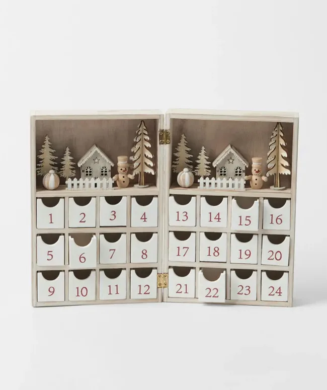 Wooden Advent calendar with small numbered drawers, decorated with snowmen, trees, and houses on top.