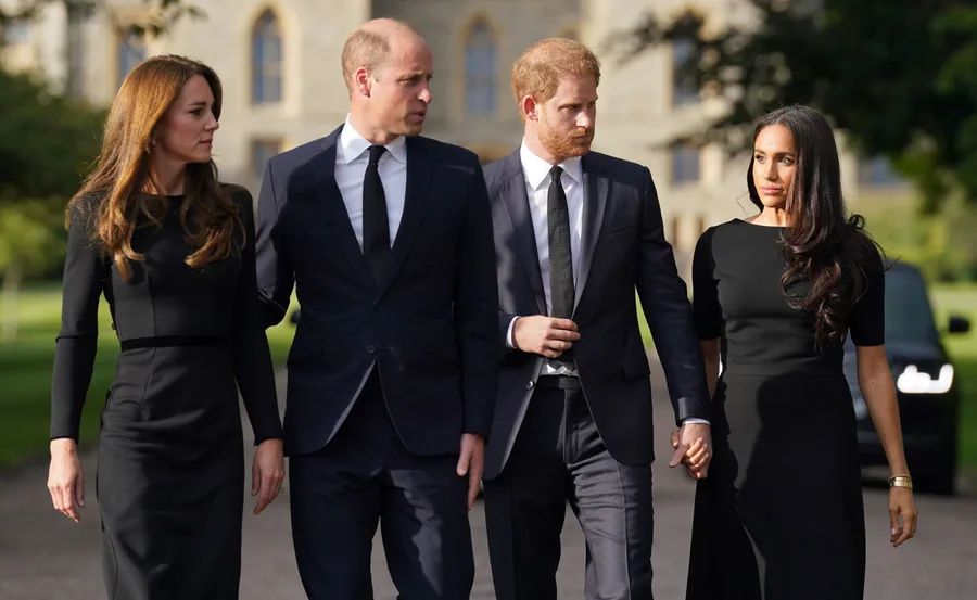 Four people in formal black attire walking side by side outdoors.