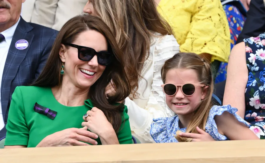 Kate Middleton smiling with a young girl at Wimbledon, both wearing sunglasses and enjoying the event.