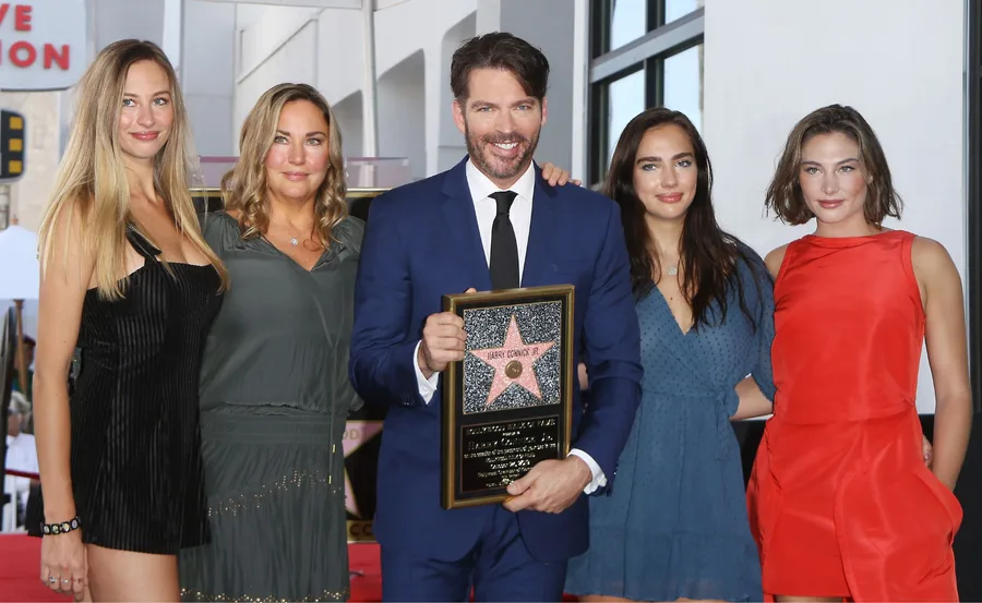 "Harry Connick Jr. with his family, holding a star plaque at a Hollywood event."