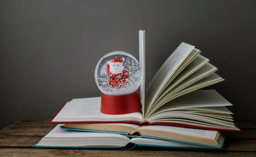Santa snow globe on open books, creating a cozy Christmas reading atmosphere.