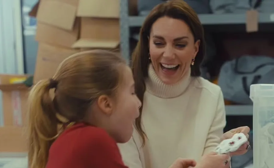 A woman laughs with a child in a room with shelves and boxes around.