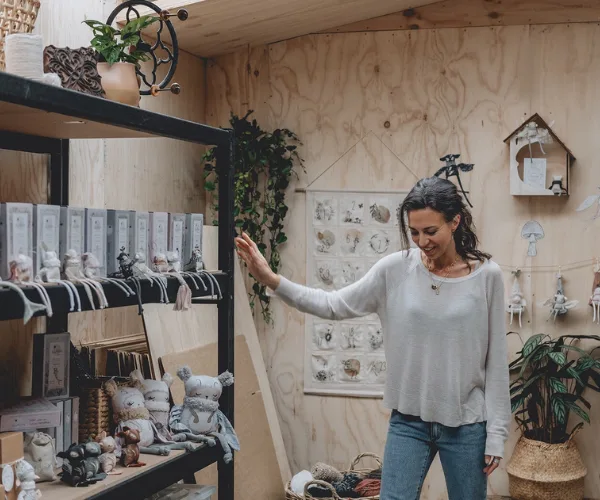 A woman in a cozy room surrounded by handmade toys and plants, creating a calming atmosphere for kids.