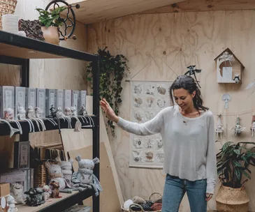 A woman in a cozy room surrounded by handmade toys and plants, creating a calming atmosphere for kids.