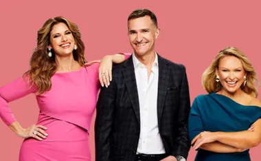 Three people posing against a pink background, smiling at the camera.