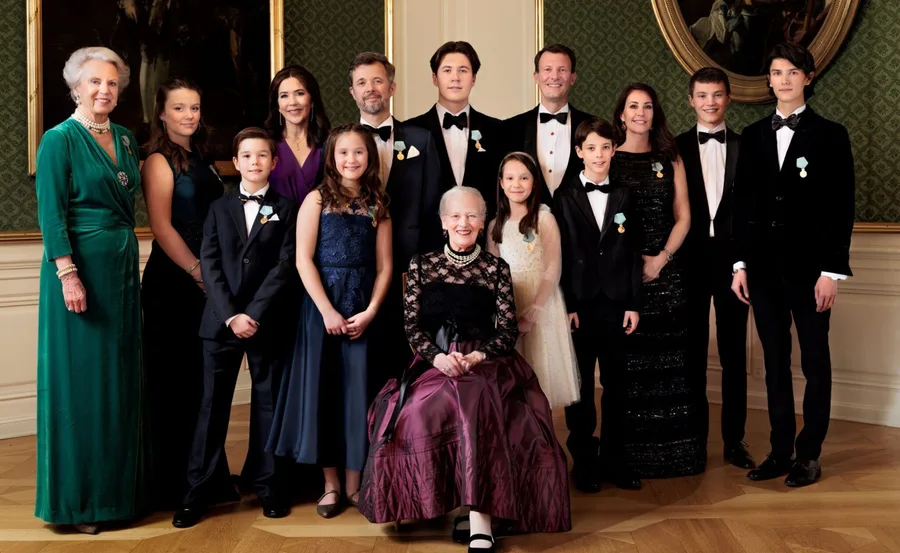 A formal group portrait of the Danish royal family in elegant attire inside a richly decorated room.