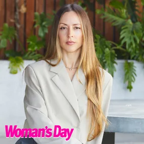 Woman with long hair in a beige blazer sitting, plants in the background, Woman's Day logo in the corner.