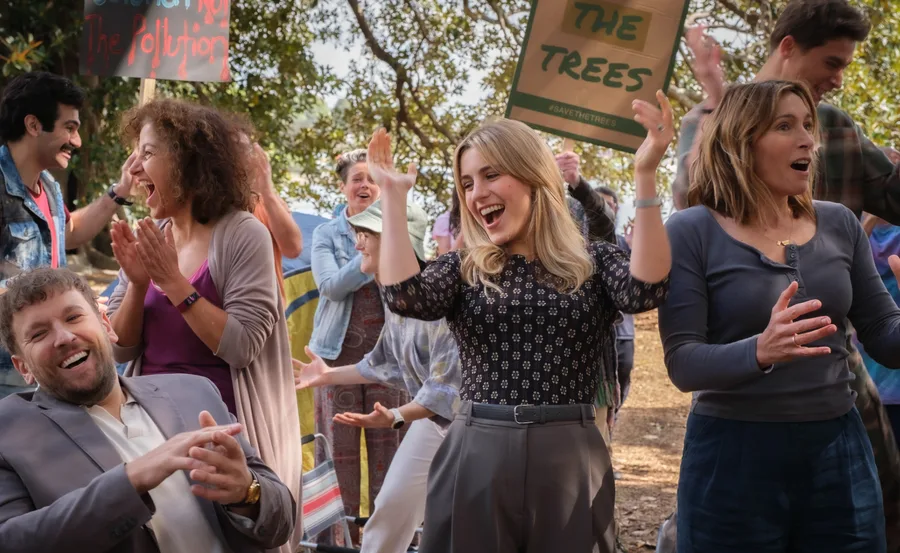 Group of people happily celebrating outdoors, holding protest signs for saving trees.