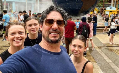 Family taking a selfie at a crowded outdoor attraction with a large globe in the background.