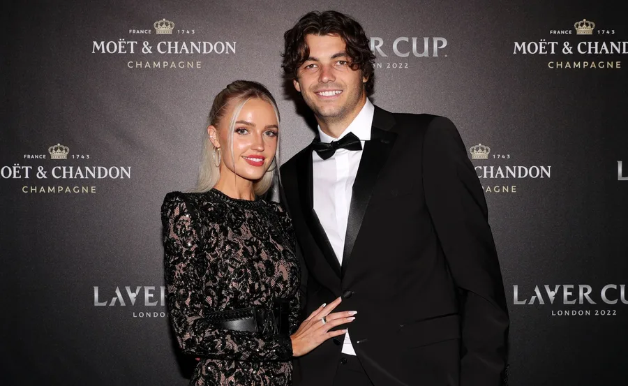 Couple in formal attire at a Moët & Chandon event backdrop, posing together with smiles.