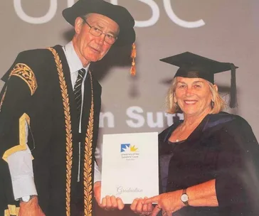 Graduating woman in cap and gown receiving a certificate from an official at a university ceremony.