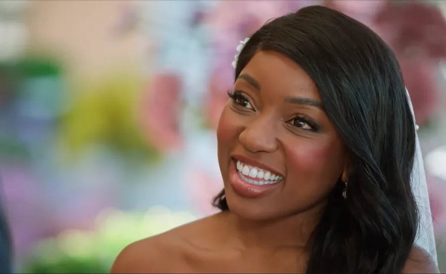 Smiling woman with long dark hair and a floral background.