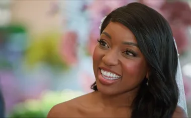 Smiling woman with long dark hair and a floral background.