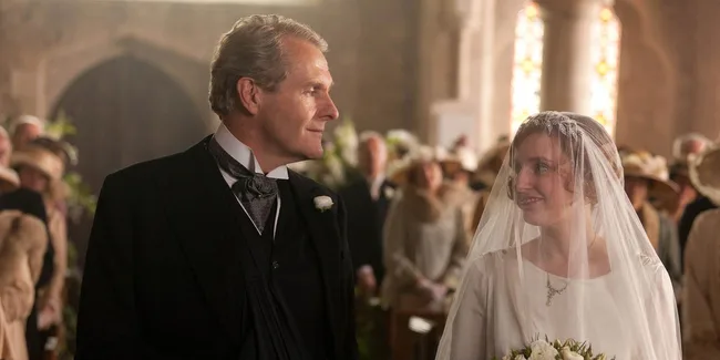 A bride and an older man, possibly her father, share a moment during a wedding ceremony in a church setting.
