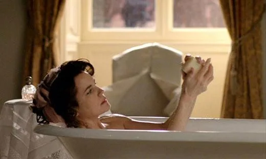 A character relaxes in a bathtub, holding an object near a window with curtains.