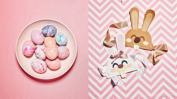 Marbled Easter eggs on a plate beside bunny masks with ribbons on pink zigzag background.