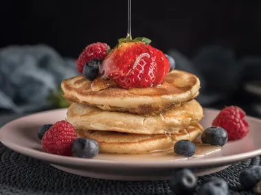 Protein pancakes topped with strawberries, blueberries and maple syrup