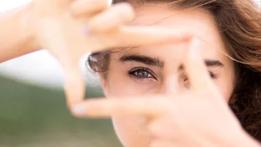 A woman using her hands to focus the camera on her eye health