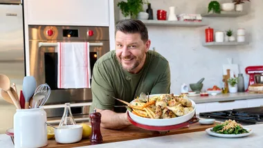 Manu Feildel holding roast chicken dish