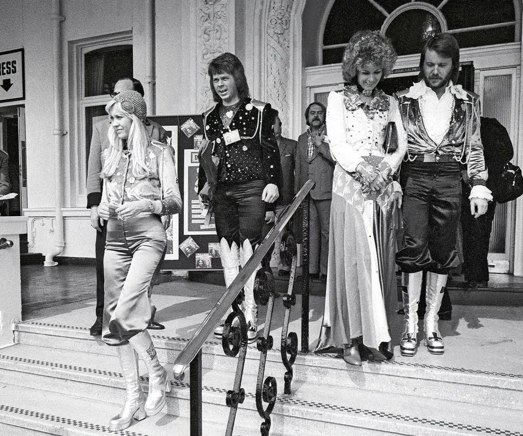 The Abba bandmates walking down the front steps of a building in black and white