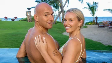 Kim Crossman and Tom Walsh looking over their shoulders from inside a pool on their honeymoon