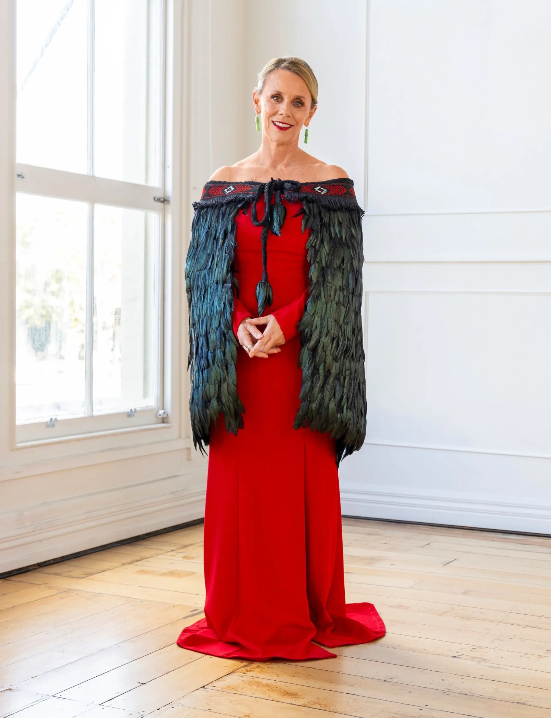 Hinewehi Mohi in a red dress with a traditional Māori coat on