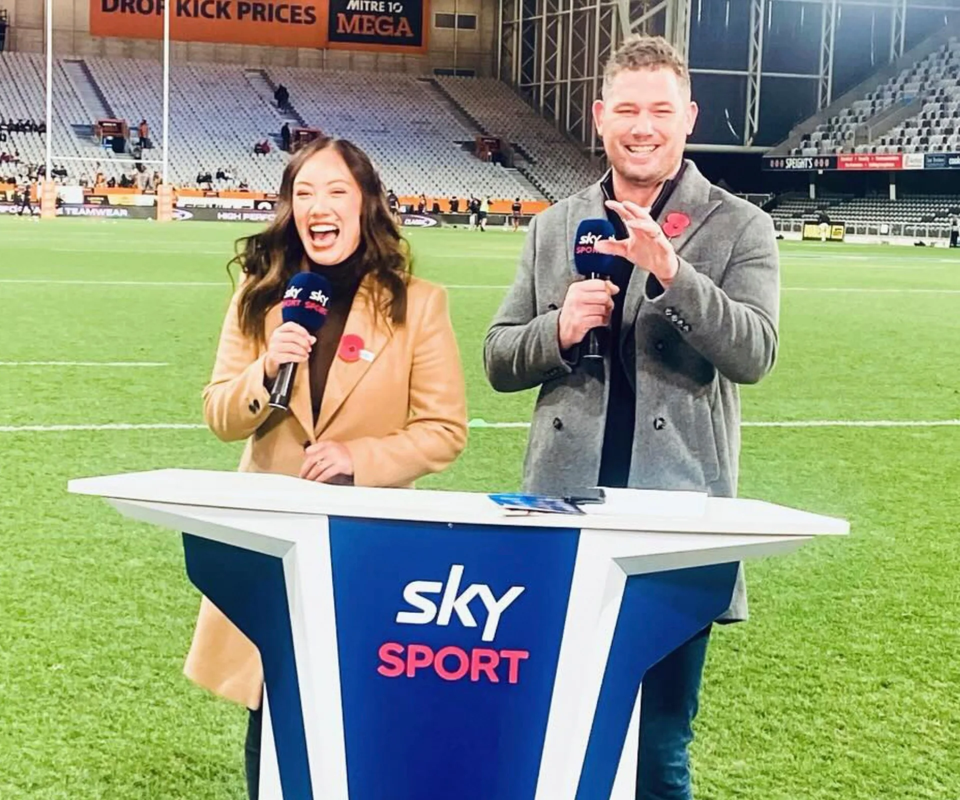 Kimberlee with colleague Joe Wheeler at the Sky Sport presentation desk on the side of a rugby field