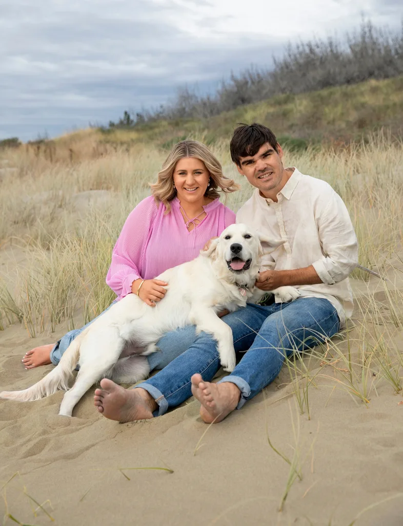 Jordan Oppert and Scruffy with their dog, Warnie sitting on sand dunes