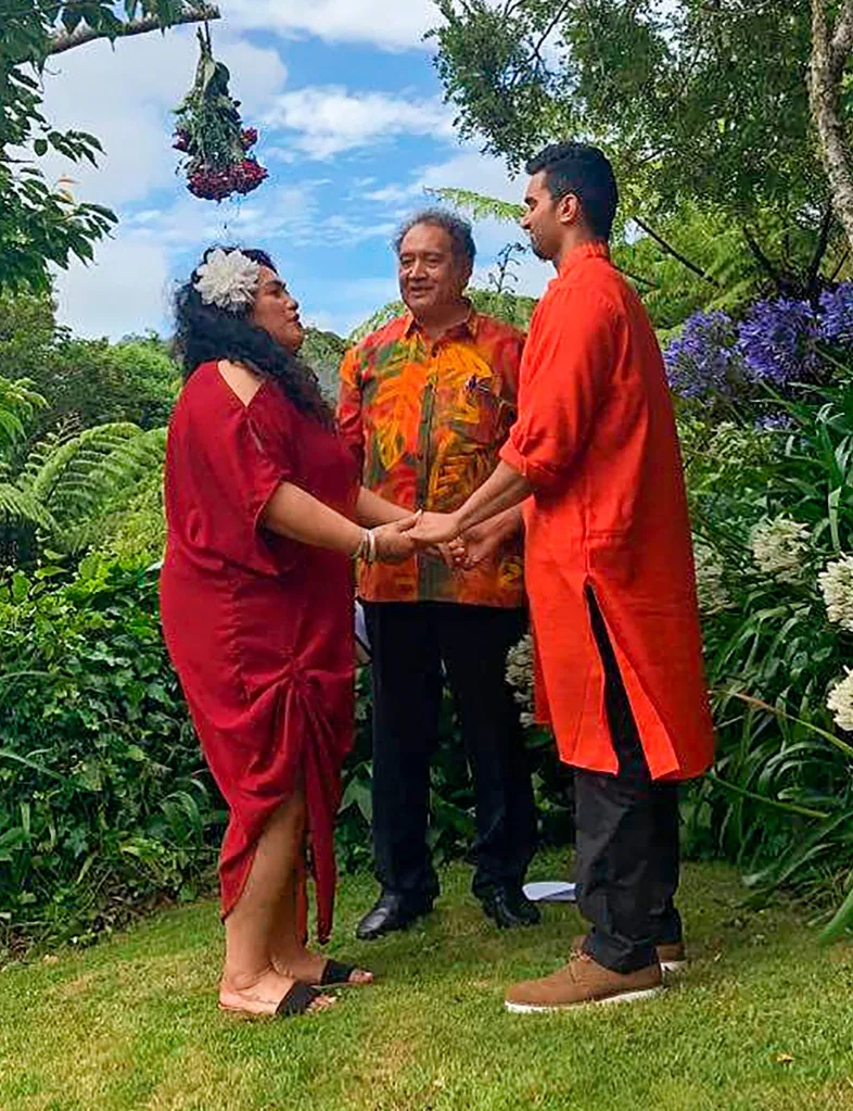 Bella and Suraj at their first wedding, holding both of each other's hands in their own