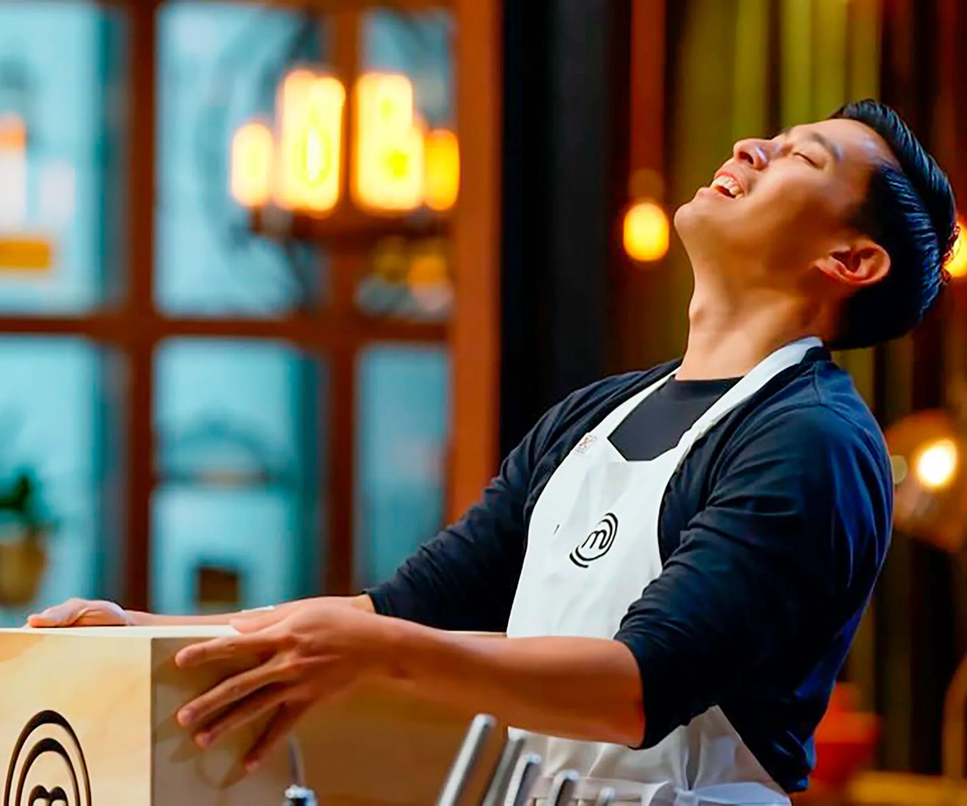 MasterChef contestant Davis holding a mystery box, throwing his head up to the sky