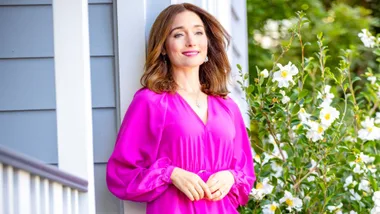 Antonia leaning on a post on her porch wearing Fluro pink