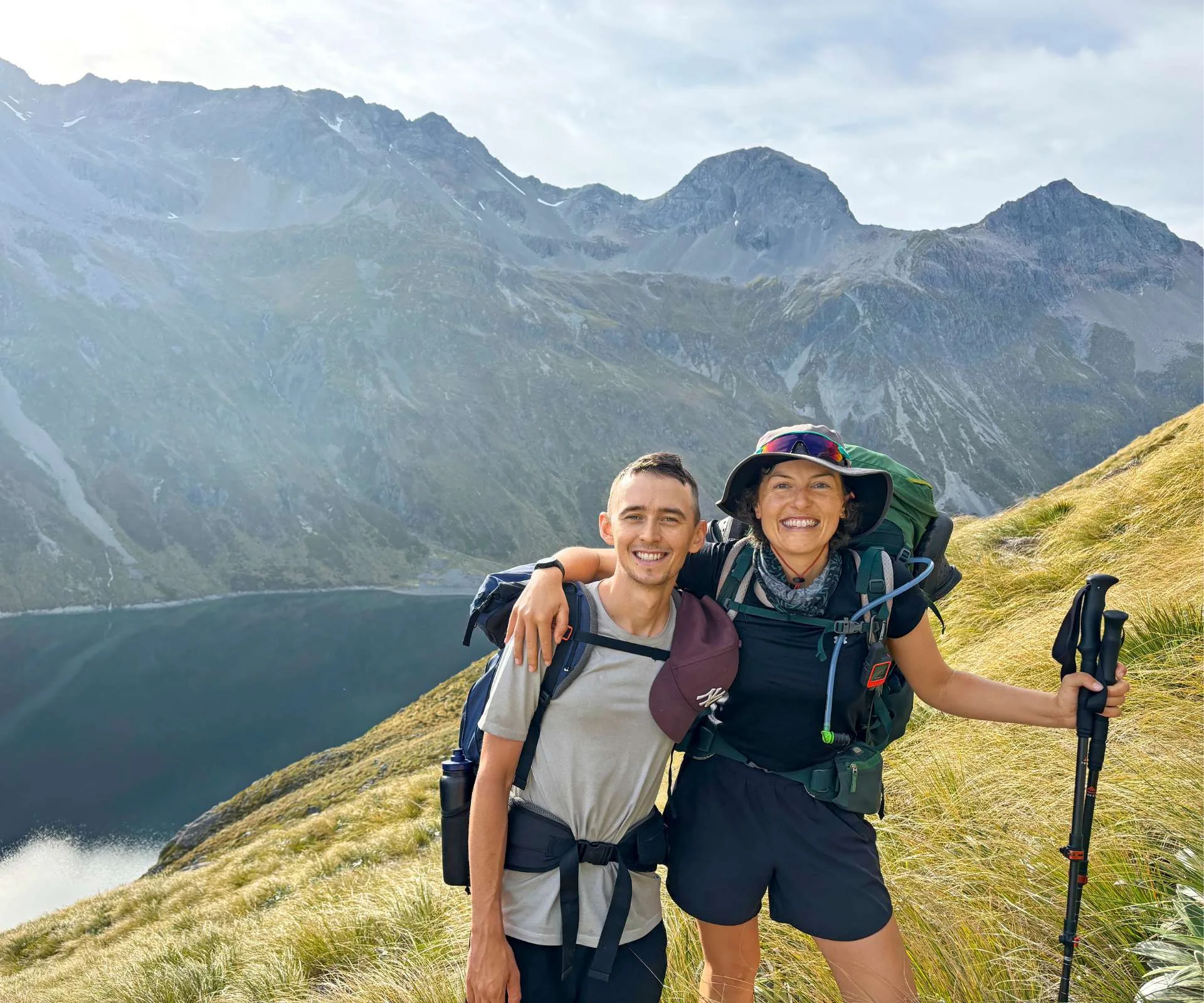 Kate and Dan on a hike in front of beautiful mountain and water scenery
